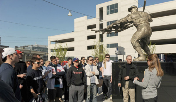 A 51̳ University class standing next to a baseball statue on a class outing.